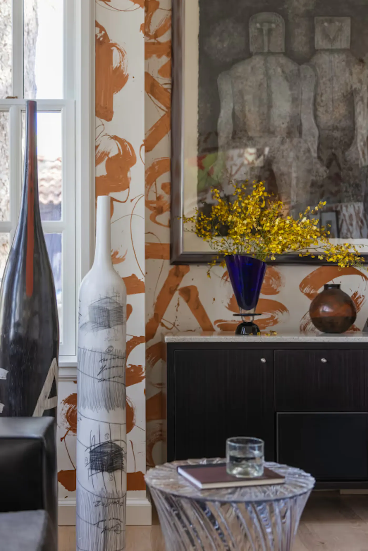 Interior design vignette with expressive mural walls, modern art, and decorative vases and floral arrangement
