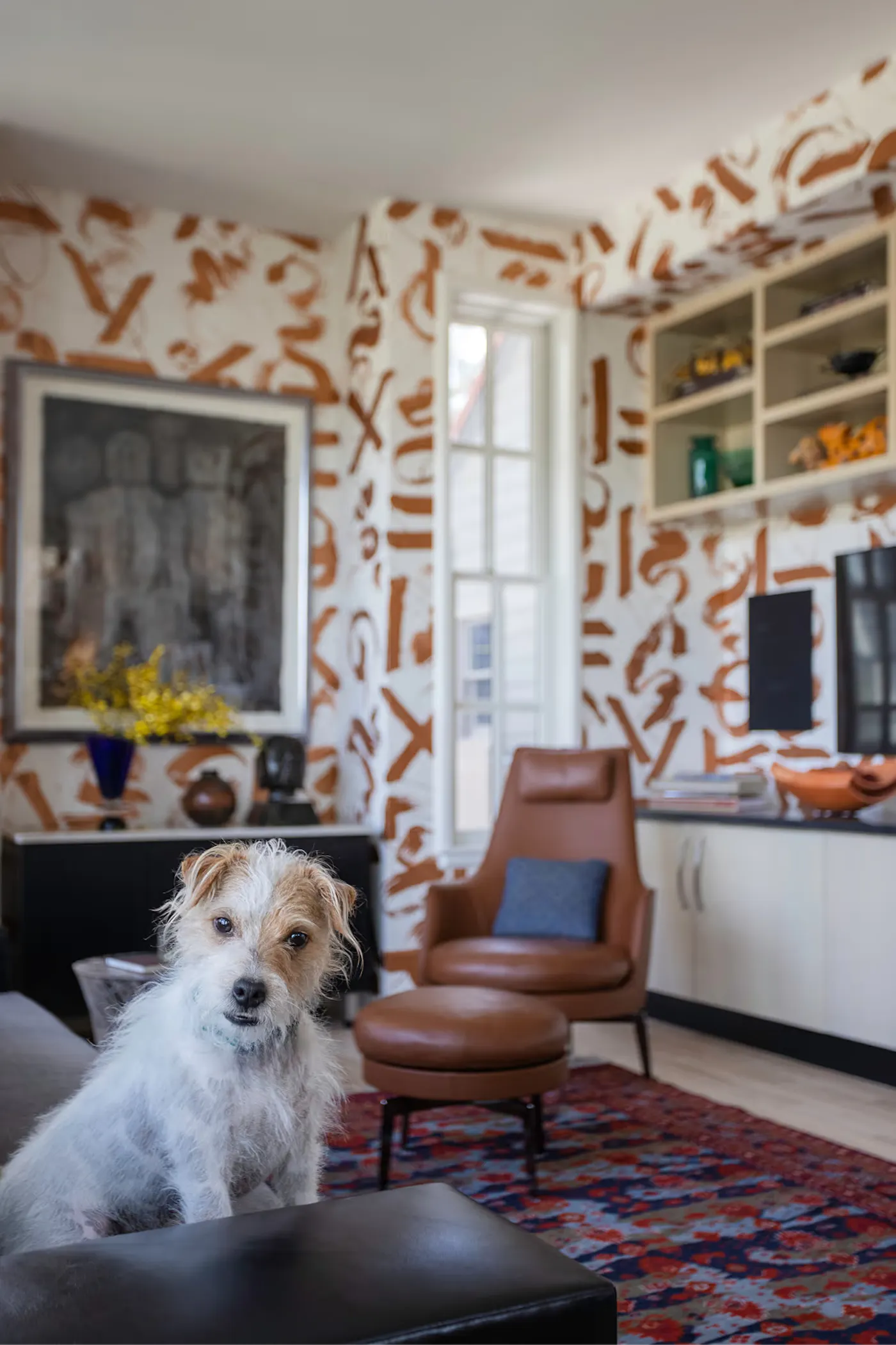 Art-filled interior with hand-painted wall pattern, built-in shelving, and cozy seating area with dog