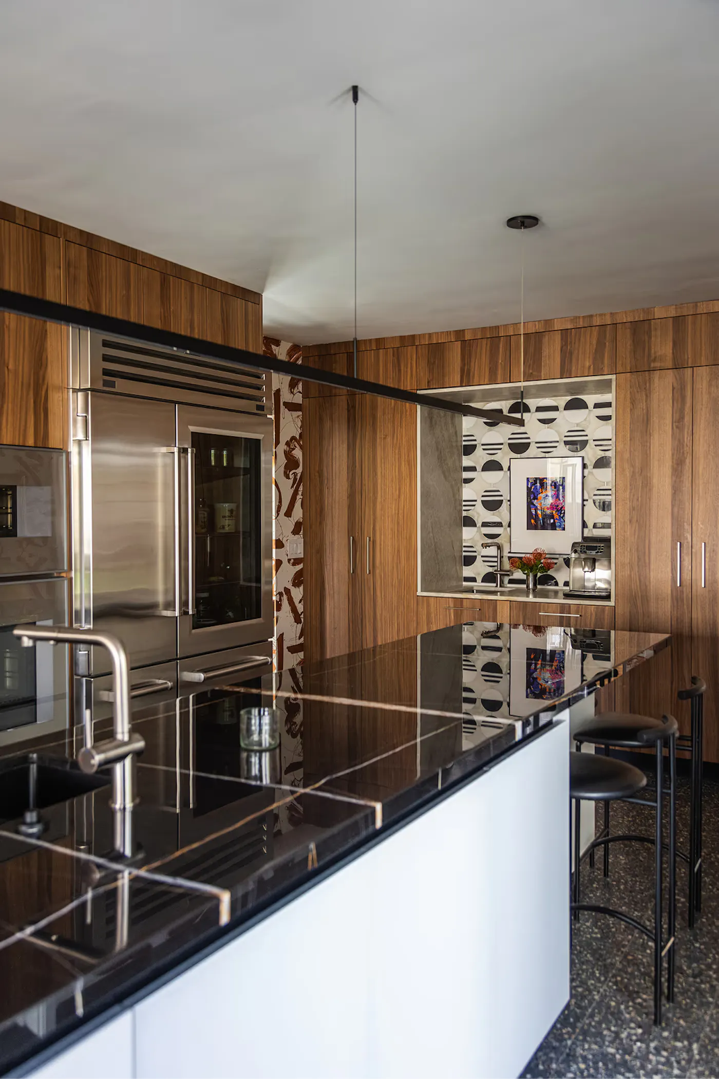 Modern kitchen design with walnut cabinetry, black stone island, stainless steel appliances, and integrated seating