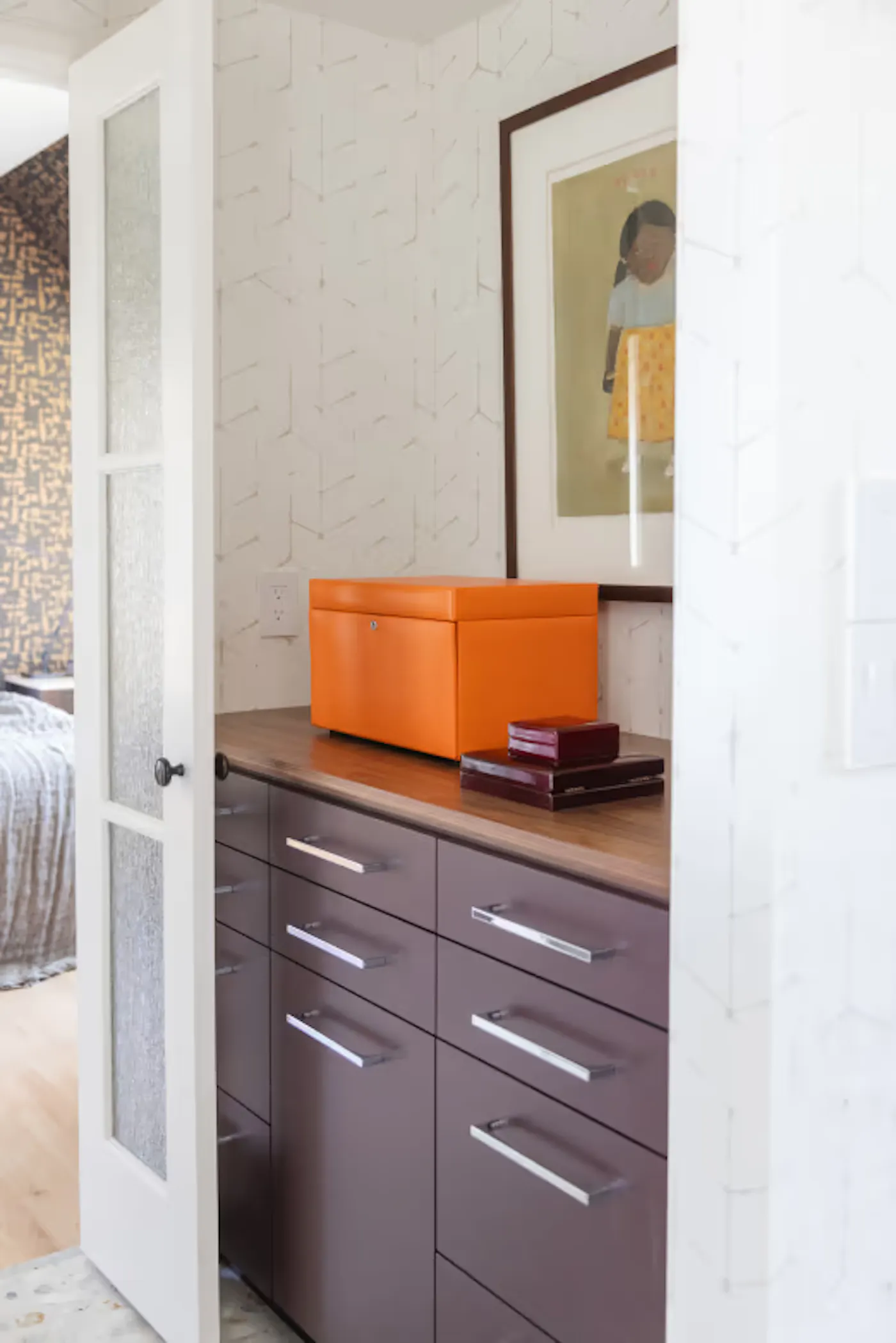 Interior design detail with custom cabinetry, wood countertop, and styled decor with bold orange accent box