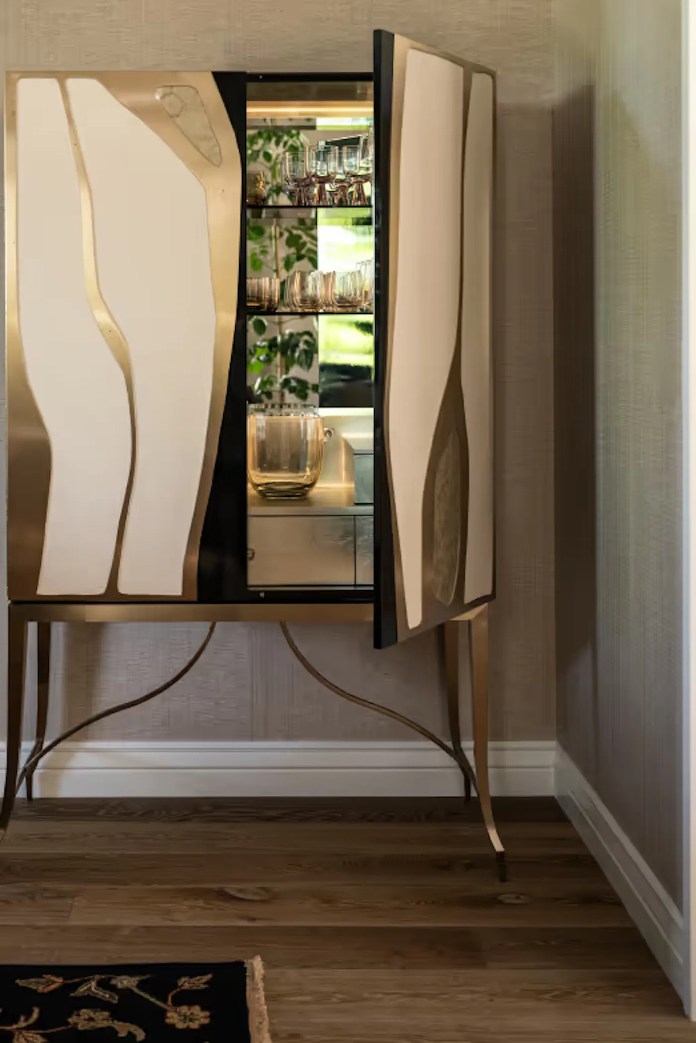 Custom bar cabinet design with sculptural doors, glass shelving, and integrated lighting in modern interior
