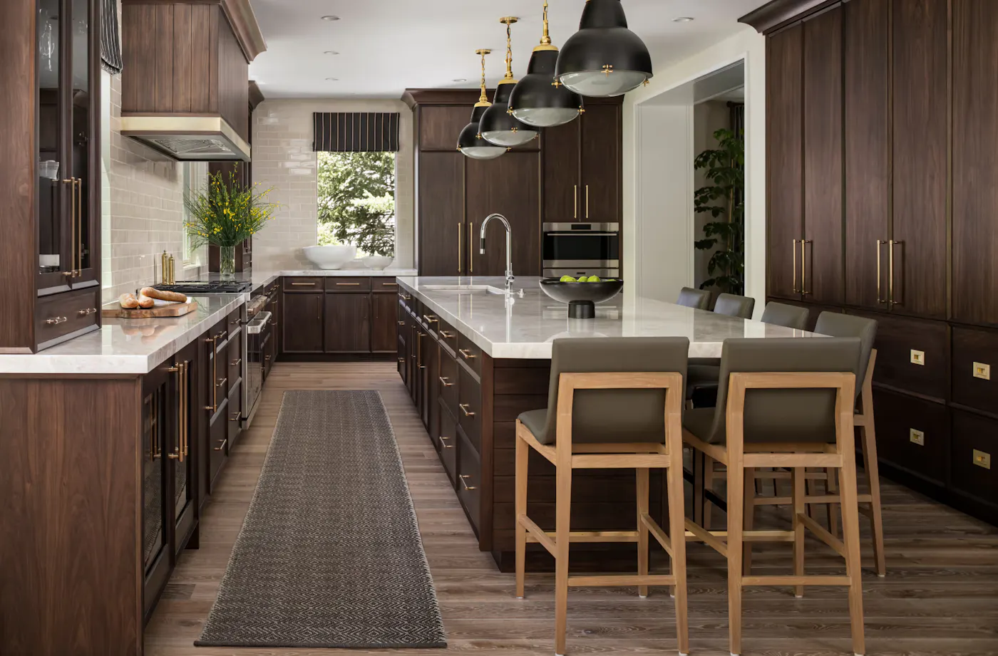 Luxury kitchen design with walnut cabinetry, large waterfall island, and brass pendant lighting