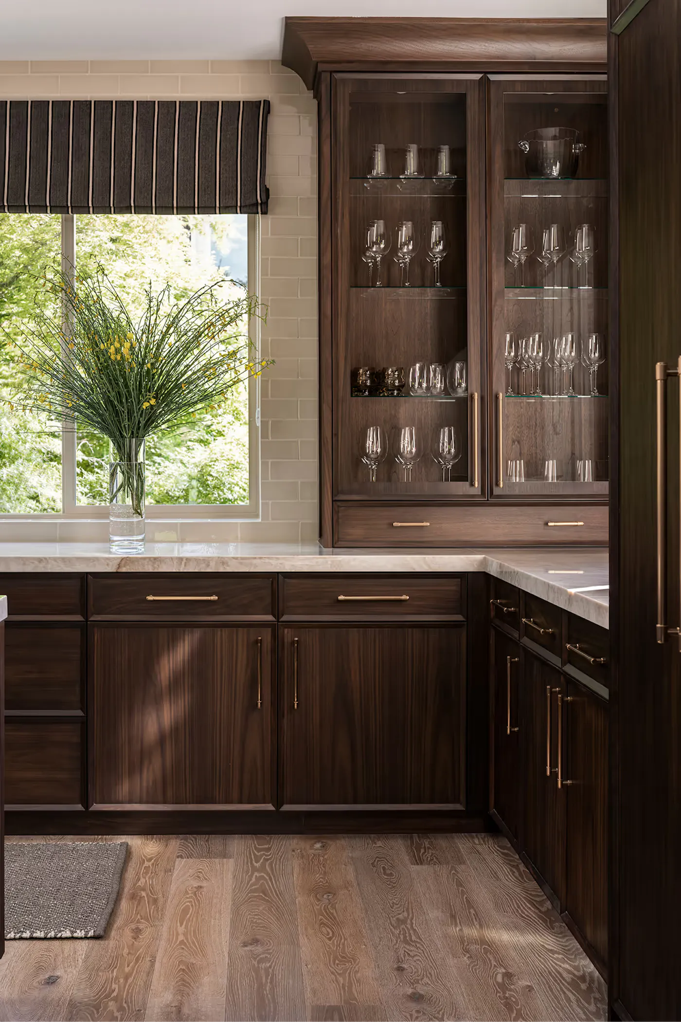 Custom walnut kitchen cabinetry with glass display cabinets and brass hardware