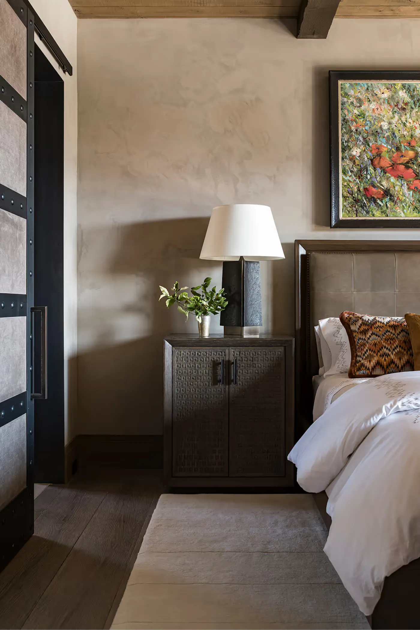 Bedroom detail with custom nightstand, textured plaster walls, and layered materials