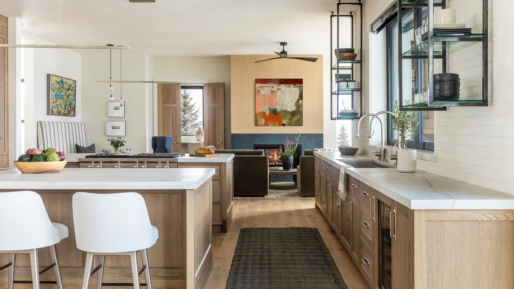 Luxury open kitchen with wood cabinetry, waterfall island, and fireplace seating area by Leslie Schofield Studio