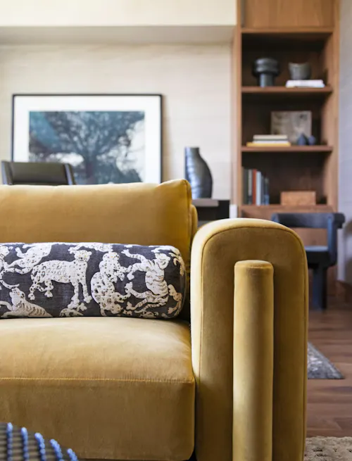 Contemporary living room detail with mustard velvet sofa and custom shelving by Leslie Schofield Studio