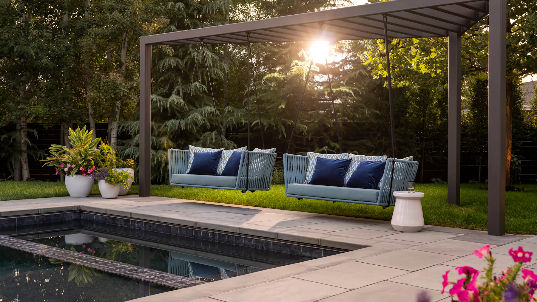 Outdoor lounge design with suspended seating, modern pool deck, and garden planters