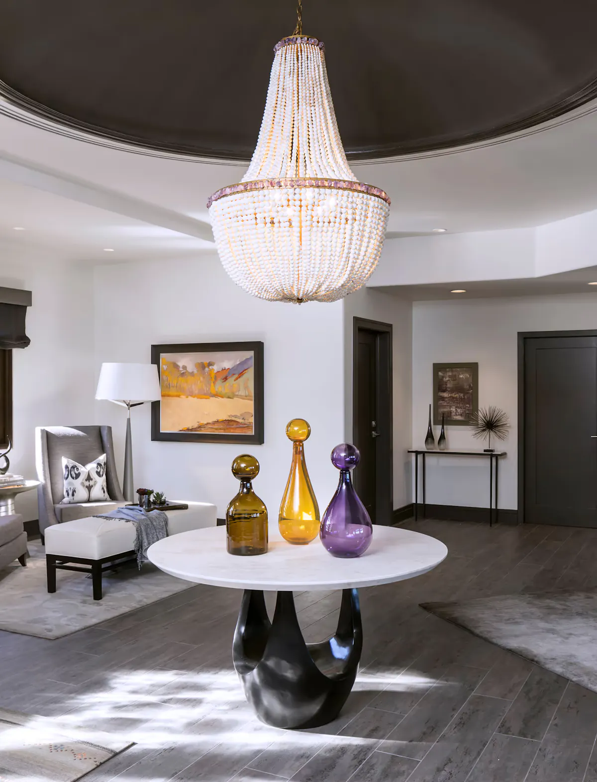 Elegant modern entryway featuring statement chandelier, round marble console table, and curated contemporary decor