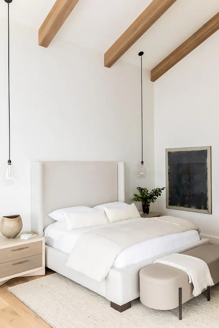 Contemporary minimalist bedroom with vaulted ceiling beams, upholstered bed, and modern pendant lighting by Leslie Schofield Studio