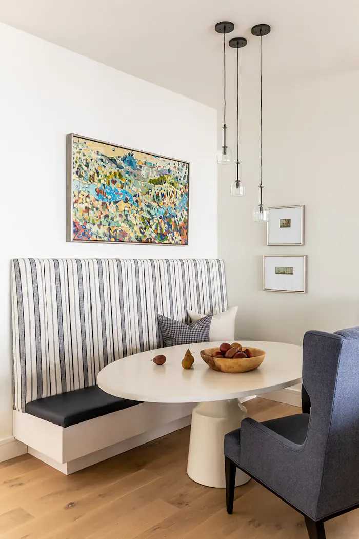 Modern dining nook featuring custom built-in banquette, round pedestal table, and layered contemporary decor accents