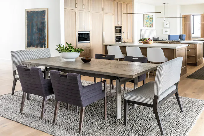 Modern open-concept dining area featuring textured dining chairs, neutral wood cabinetry, and contemporary pendant lighting