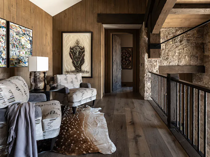 Rustic luxury mountain home sitting area with reclaimed wood walls, natural stone fireplace, and western-inspired interior design by Leslie Schofield Studio