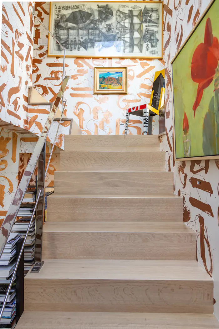 Artistic contemporary staircase featuring bold abstract wallpaper, curated gallery artwork, and minimalist light oak stair design by Leslie Schofield Studio