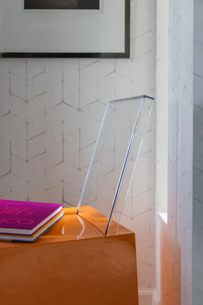 Modern interior styling detail featuring geometric wallpaper, acrylic decor accents, and colorful coffee table books in a contemporary luxury home