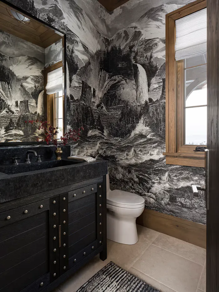 Dramatic luxury powder room featuring immersive black and white mountain landscape wallpaper, dark wood vanity, and moody contemporary finishes