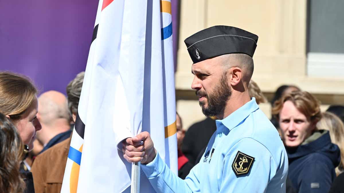 Le gendarme Hugues Duboscq, ancien nageur olympique et sportif de haut niveau de la Gendarmerie, aujourd'hui plongeur au sein du peloton sur sûreté maritime et portuaire de la gendarmerie maritime du Havre, portant le drapeau officiel des Jeux olympiques. (Photo: L.Picard / L'Essor)