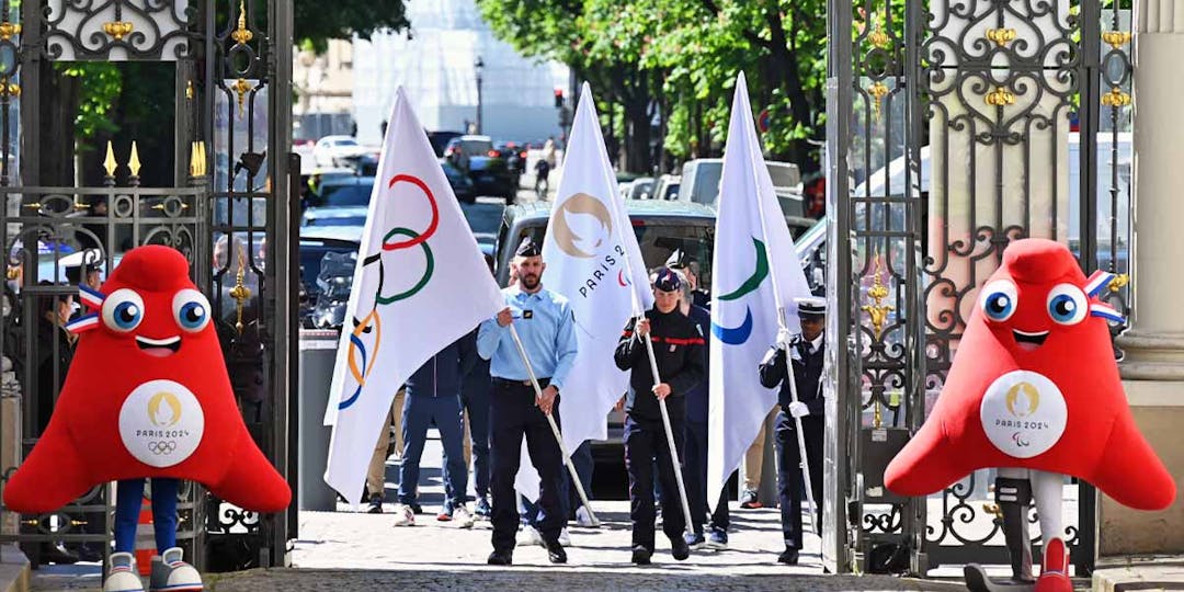 Le gendarme Hugues Duboscq, une sapeur-pompier et une policière portant les drapeaux des Jeux olympiques et paralympiques (JOP) de Paris 2024, à l'entrée du ministère de l'Intérieur, le 23 avril 2024. (Photo: L.Picard / L'Essor)