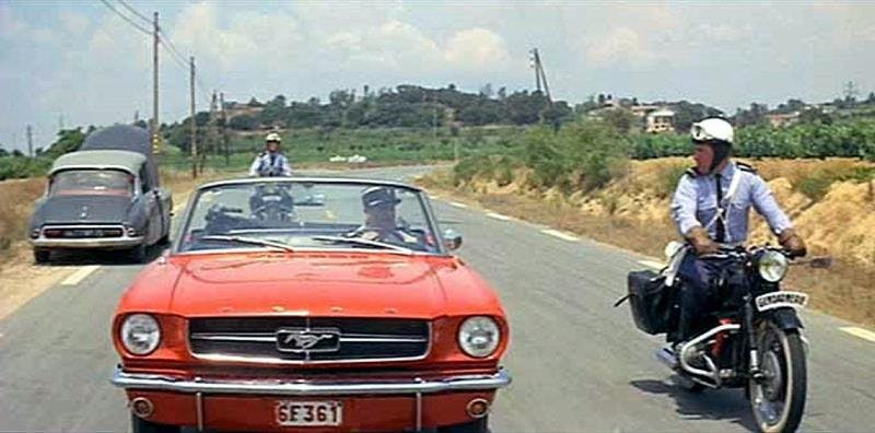 Louis de Funès, au volant d'une Ford Mustang et escorté par deux motocyclistes de la Gendarmerie au guidon de moto BMW R60. (Extrait du film Le Gendarme de Saint-Tropez, 1964).