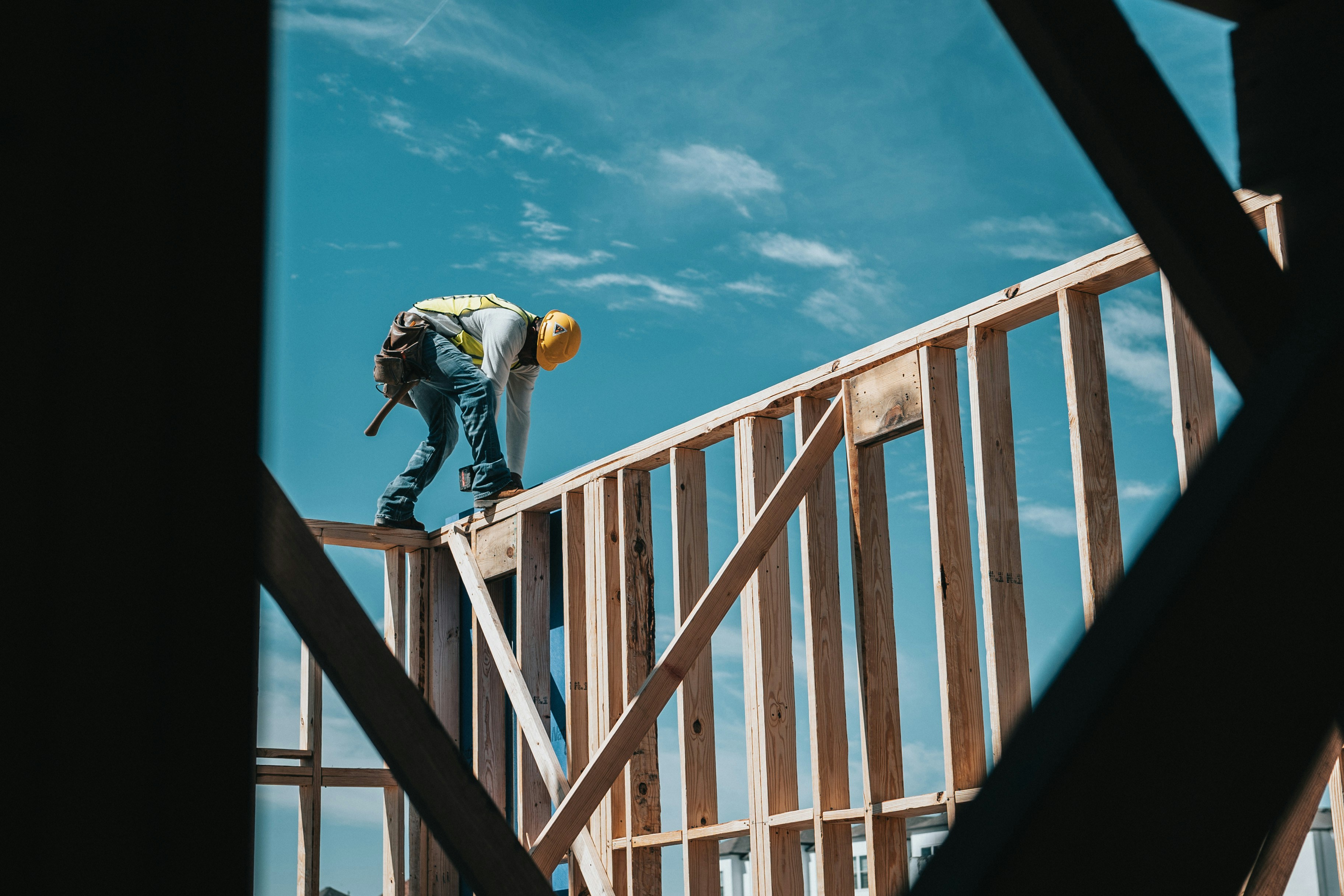 Photo of a construction worker working on top of a framed wall