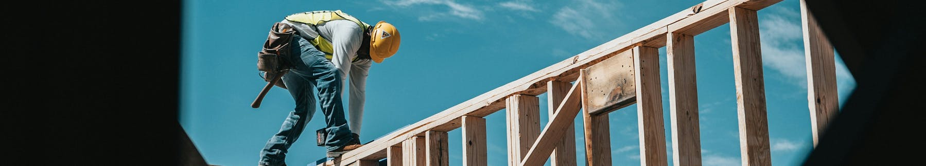 Photo of a construction worker working on top of a framed wall
