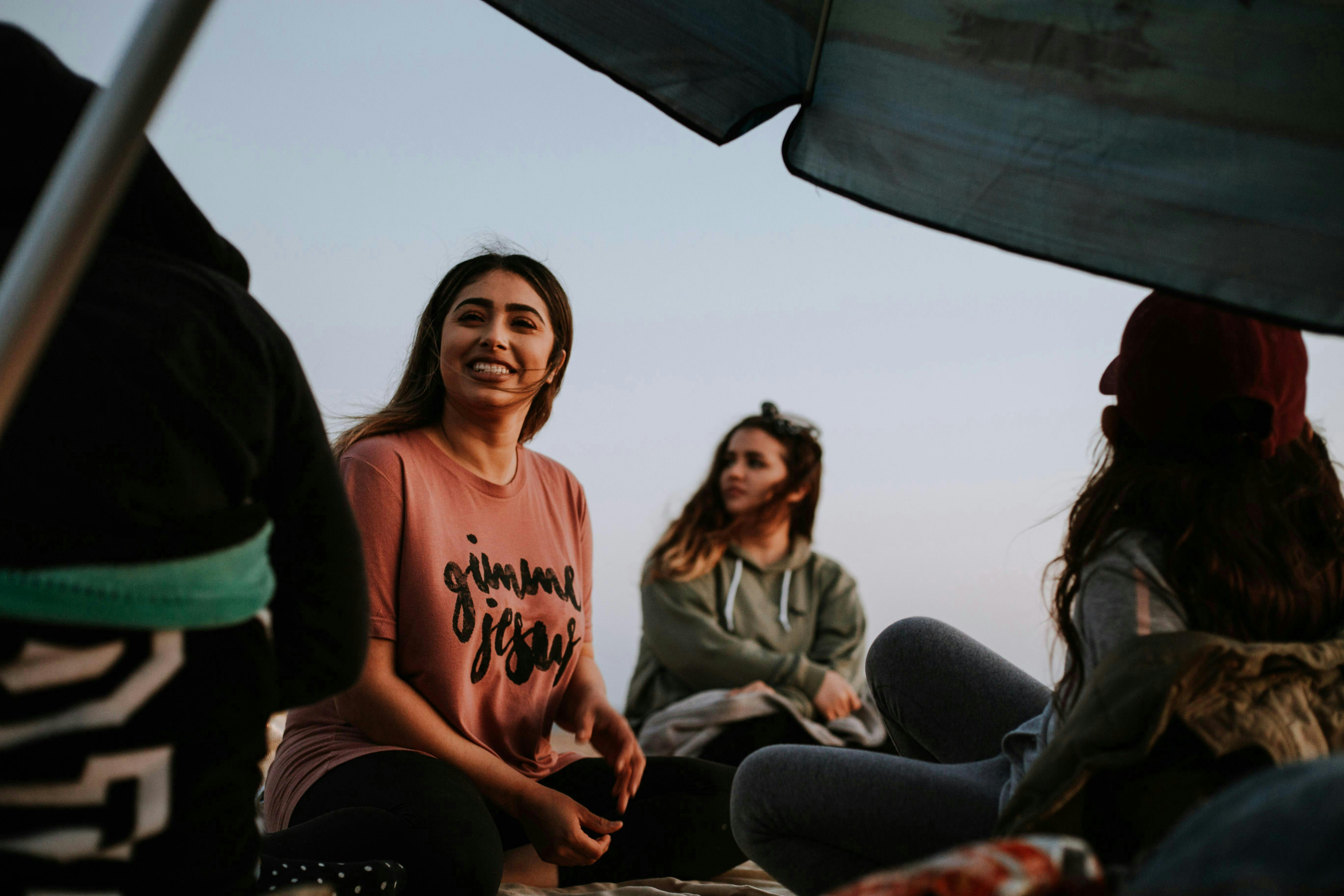 Photo of women sitting on a windy beach smiling and chatting
