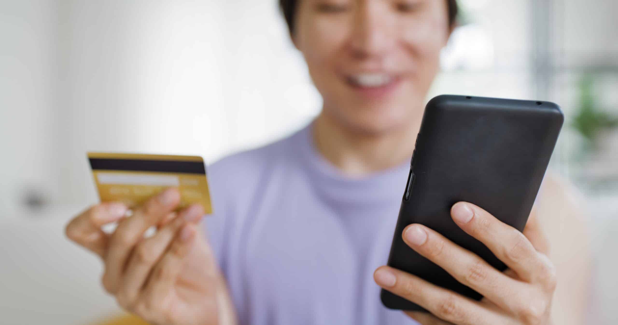 Gen Z person holding their phone and a debit card