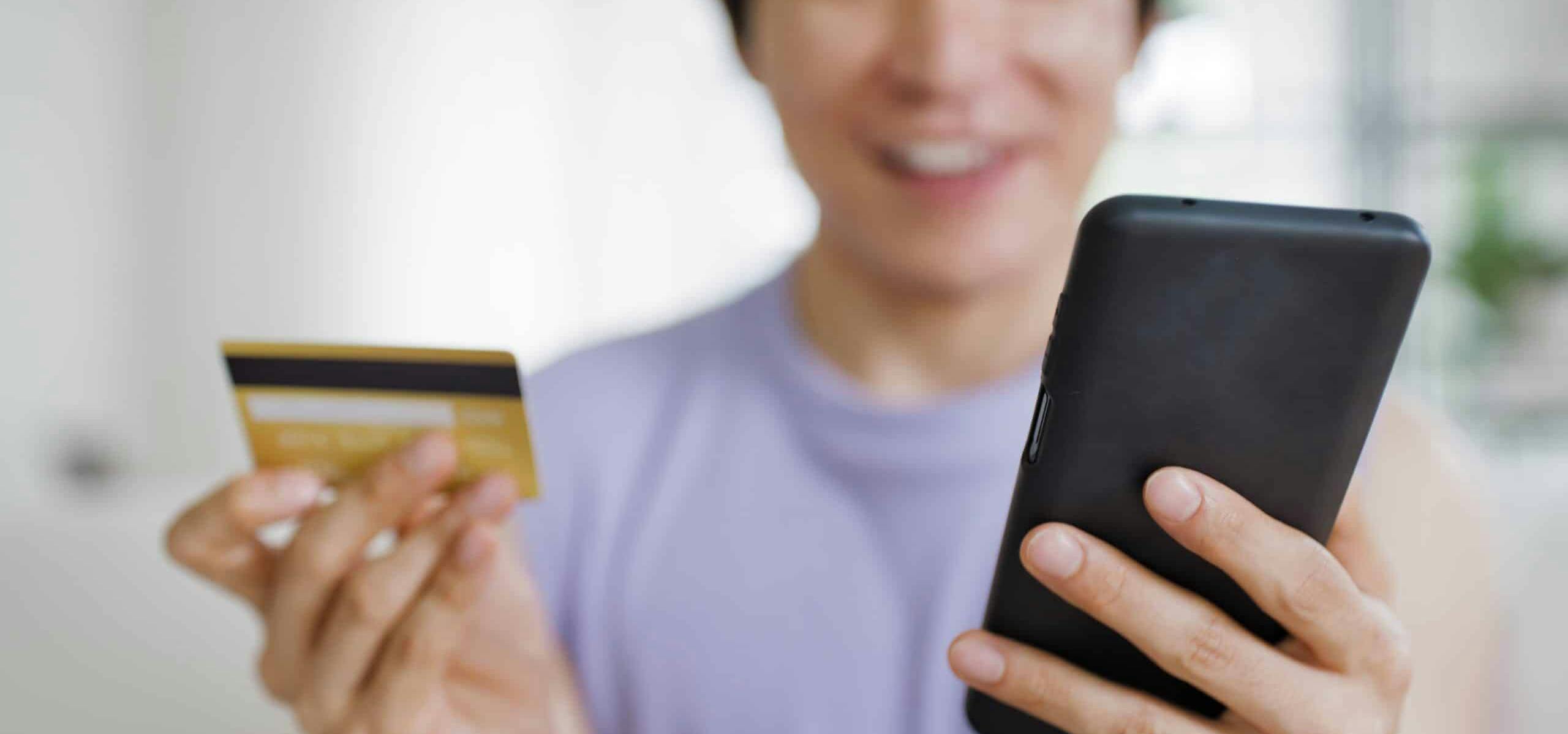 Gen Z person holding their phone and a debit card