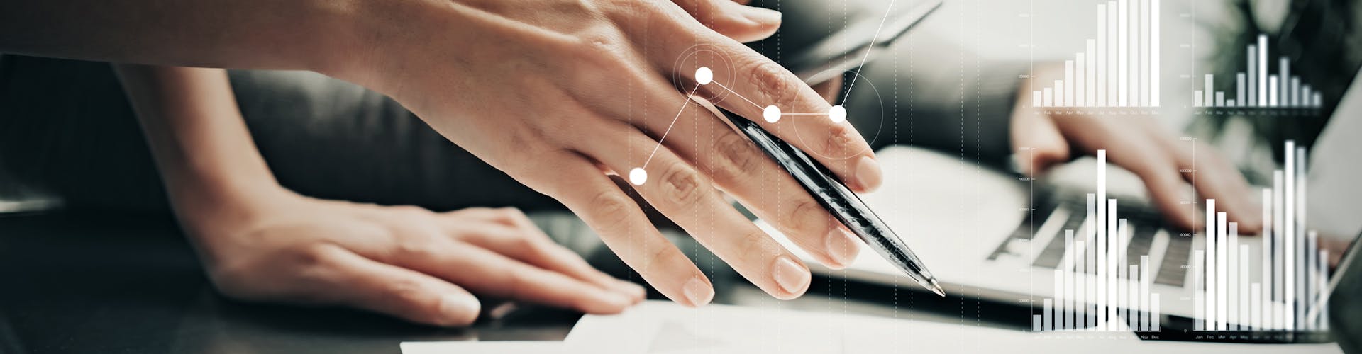 A hand holding a pen above sheets of paper. Stats and growth icons on screen.