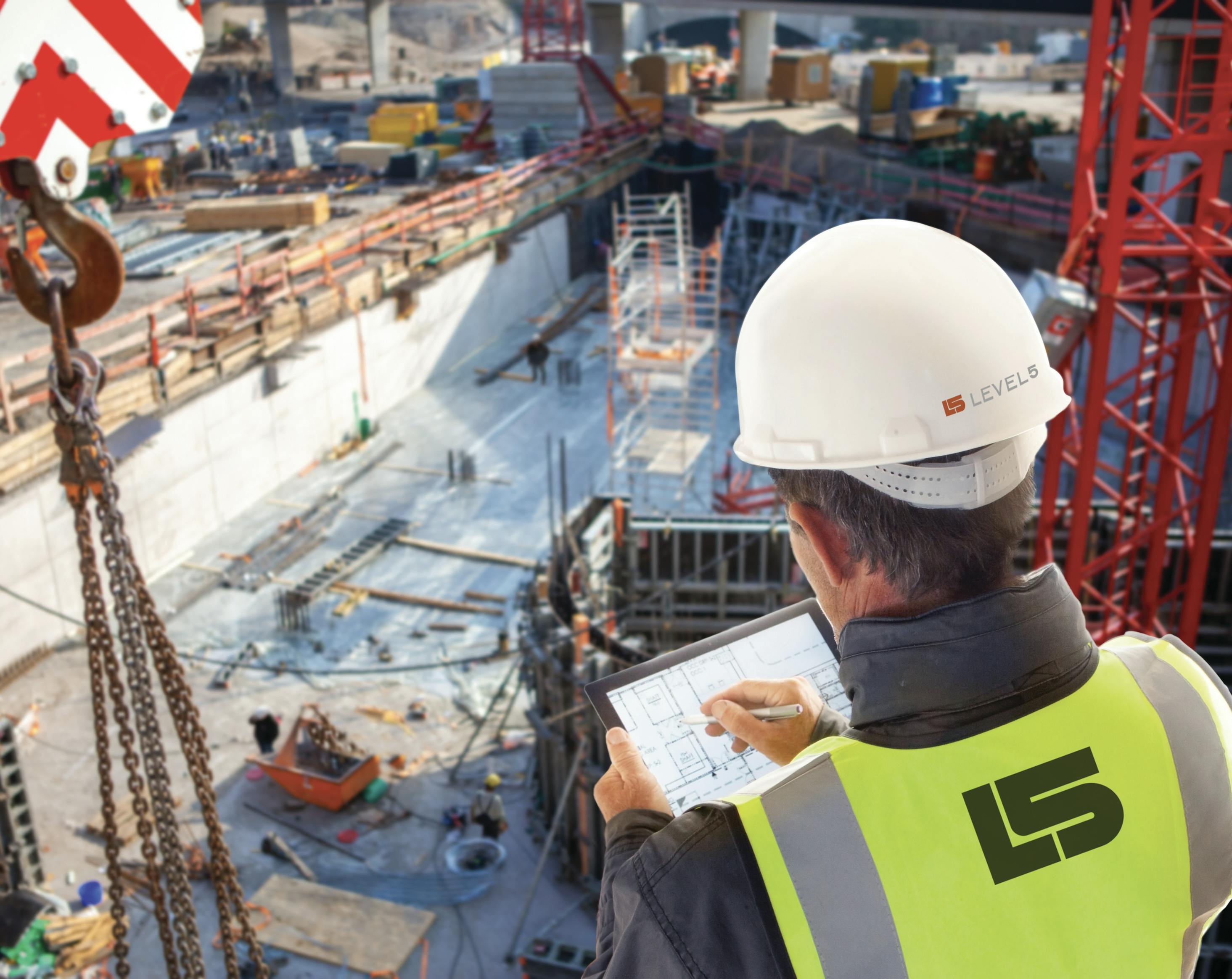 construction worker, aerial view above site, writing on tablet