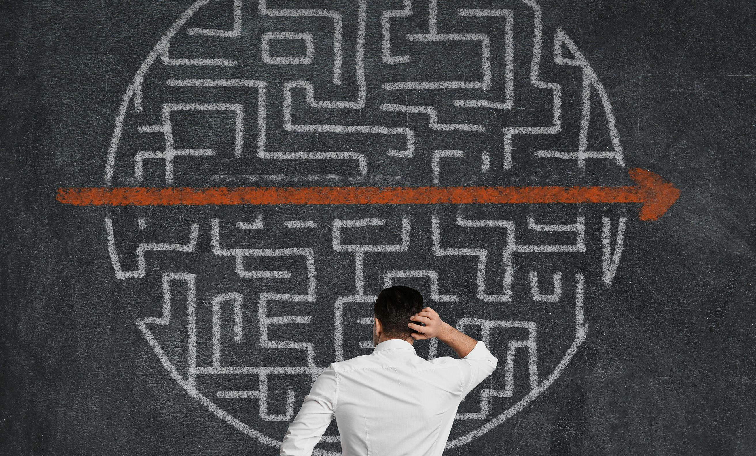 Person standing in front of complex chart with arrow cutting through it.