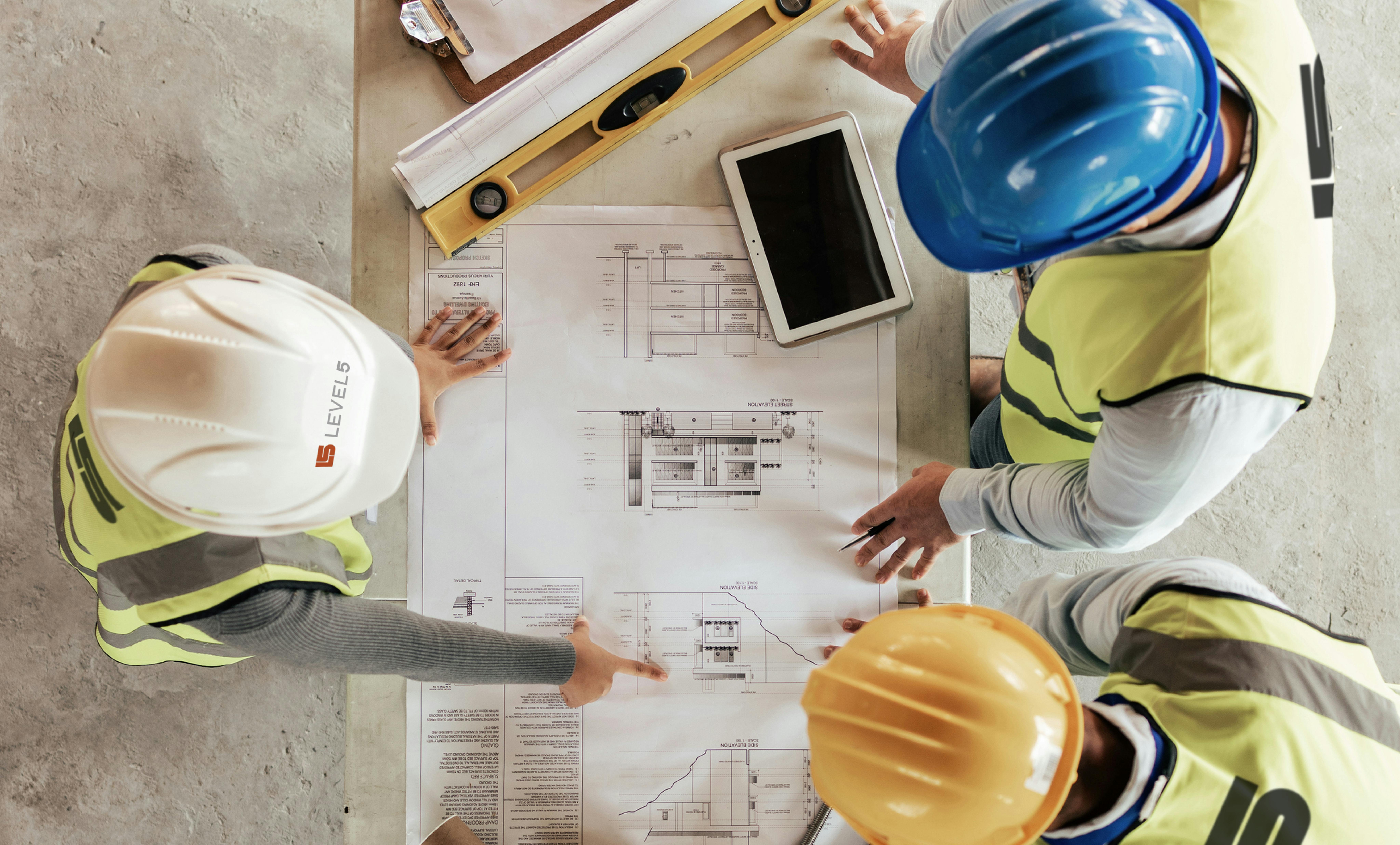 Construction workers gathered around a blueprint