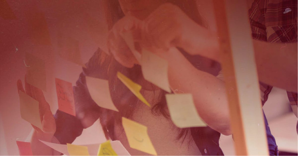 Close-up of two people putting Post-It notes on a wall