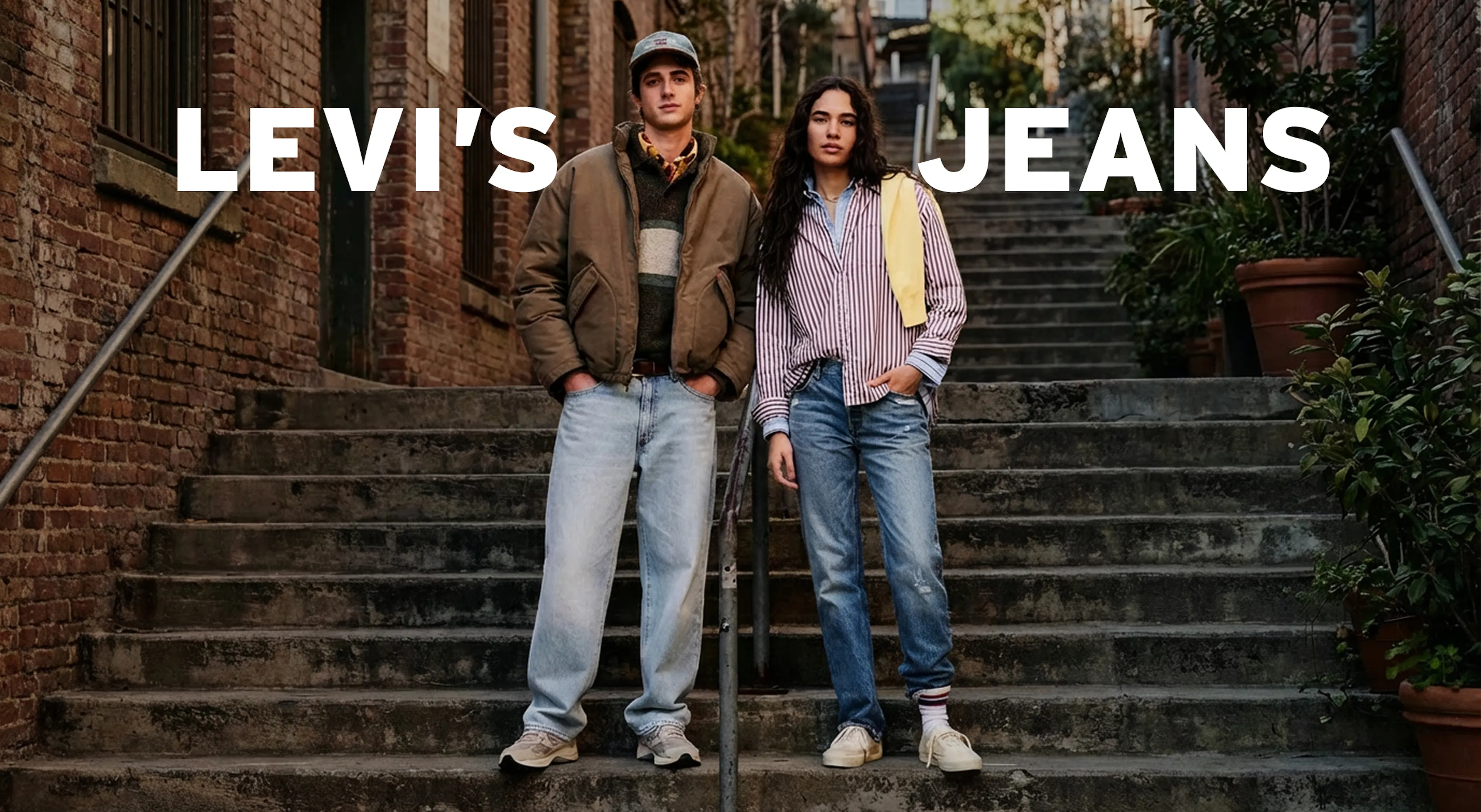 A man and woman on a set of stairs modelling Levi's Jeans