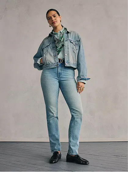 Woman in light-wash denim jacket and jeans set showing women's fit guide.