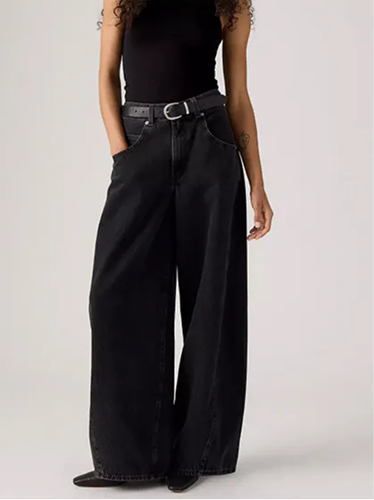 Woman in black relaxed-fit jeans and sleeveless top showcasing loose and baggy streetwear style.