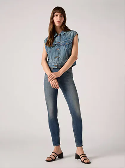 Woman dressed in skinny jeans and sleeveless denim top with casual stance.