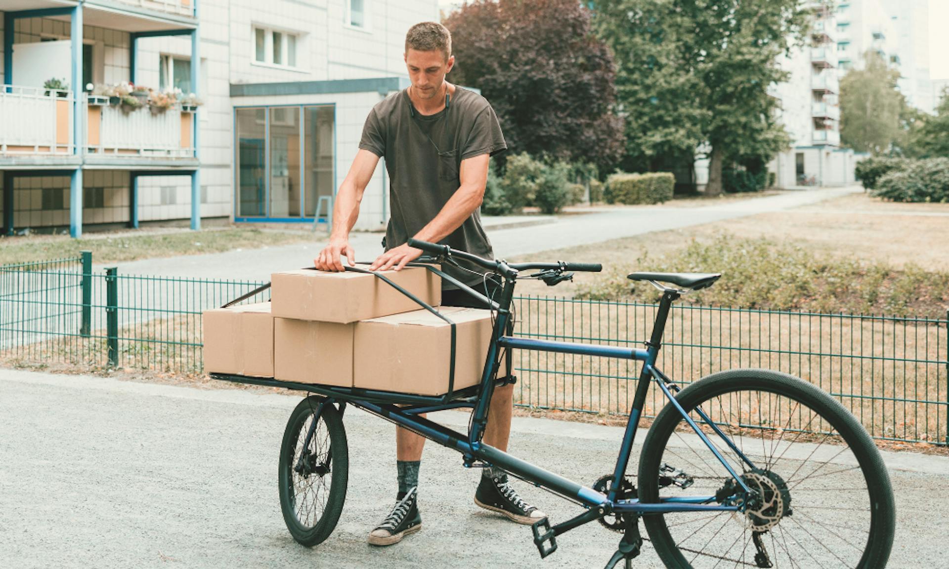 Man met cargo fiets met dozen op in stad