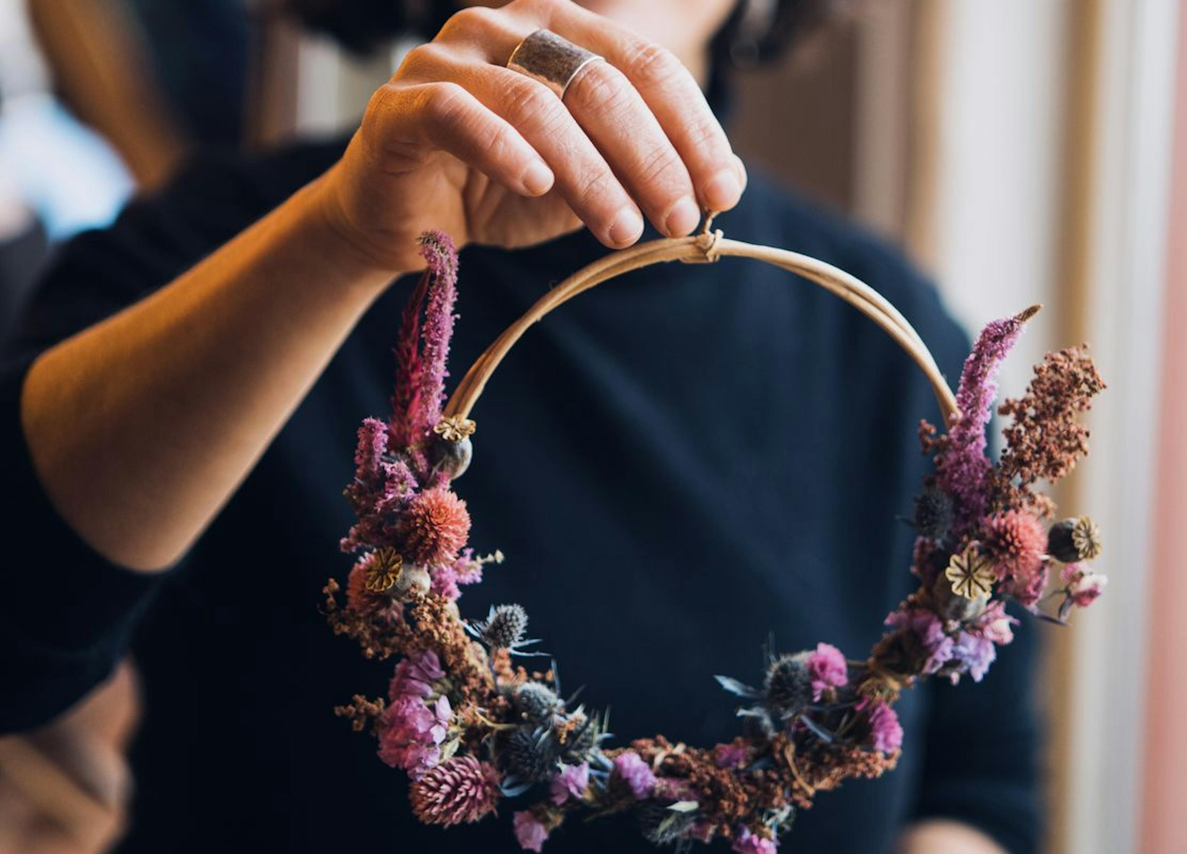 Foto met deelnemer van een droogbloemenkrans workshop met het resultaat in haar hand