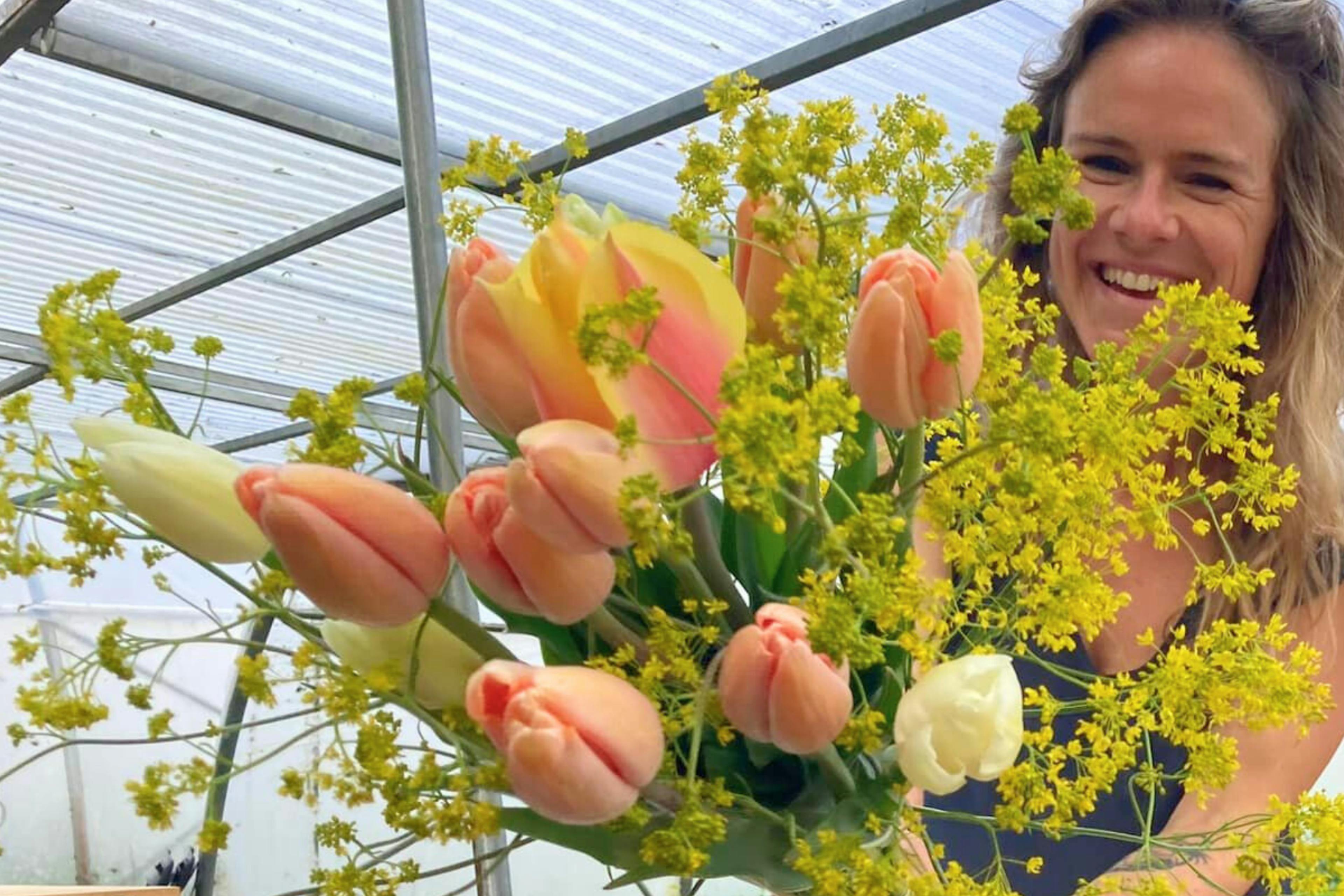 Foto van een vrouw die een boeket tulpen voor zich uit houdt op de lentemarkt op De Wassende Maan