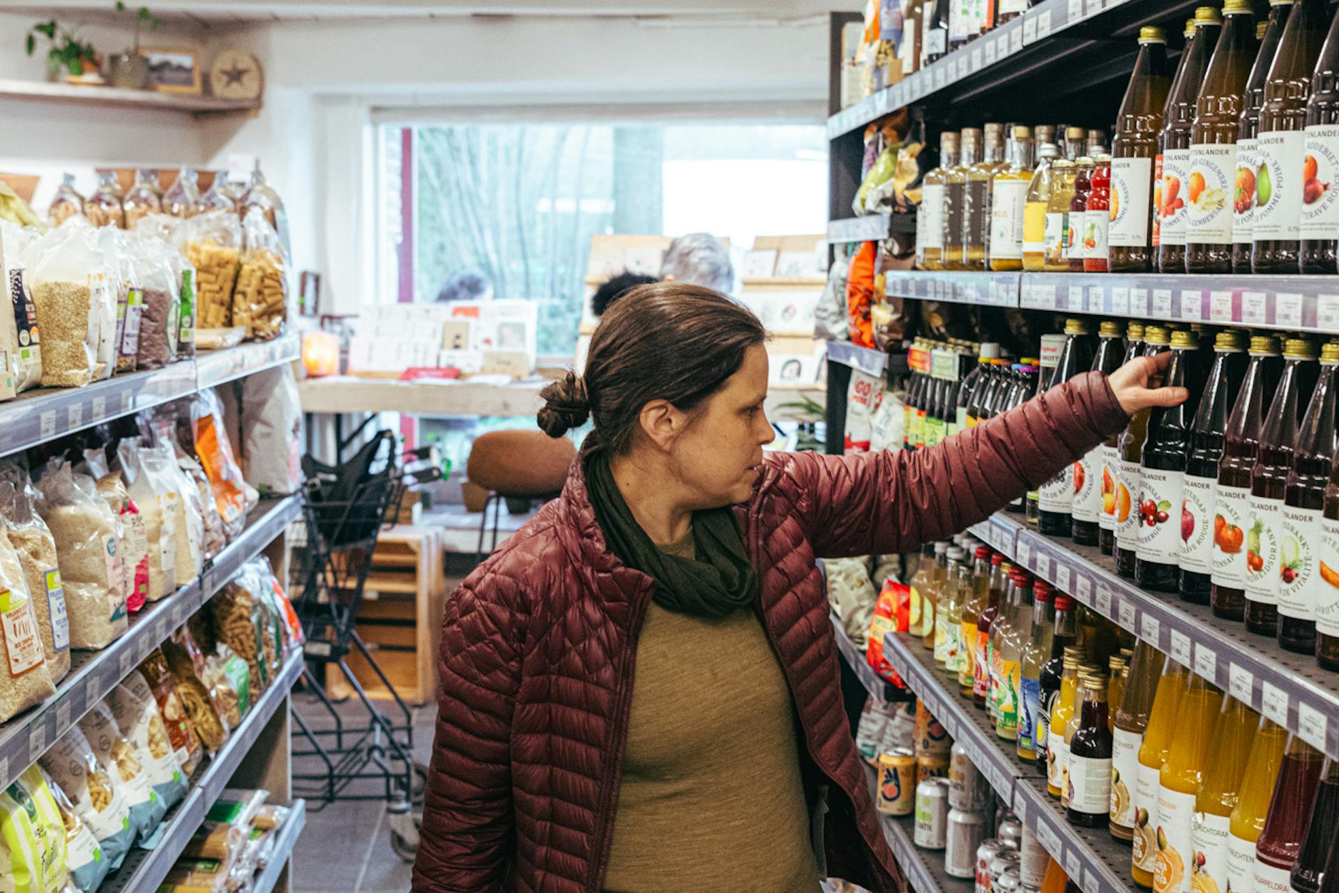 Sofie in de bio-superette die een fles sap uit het drankenrayon neemt