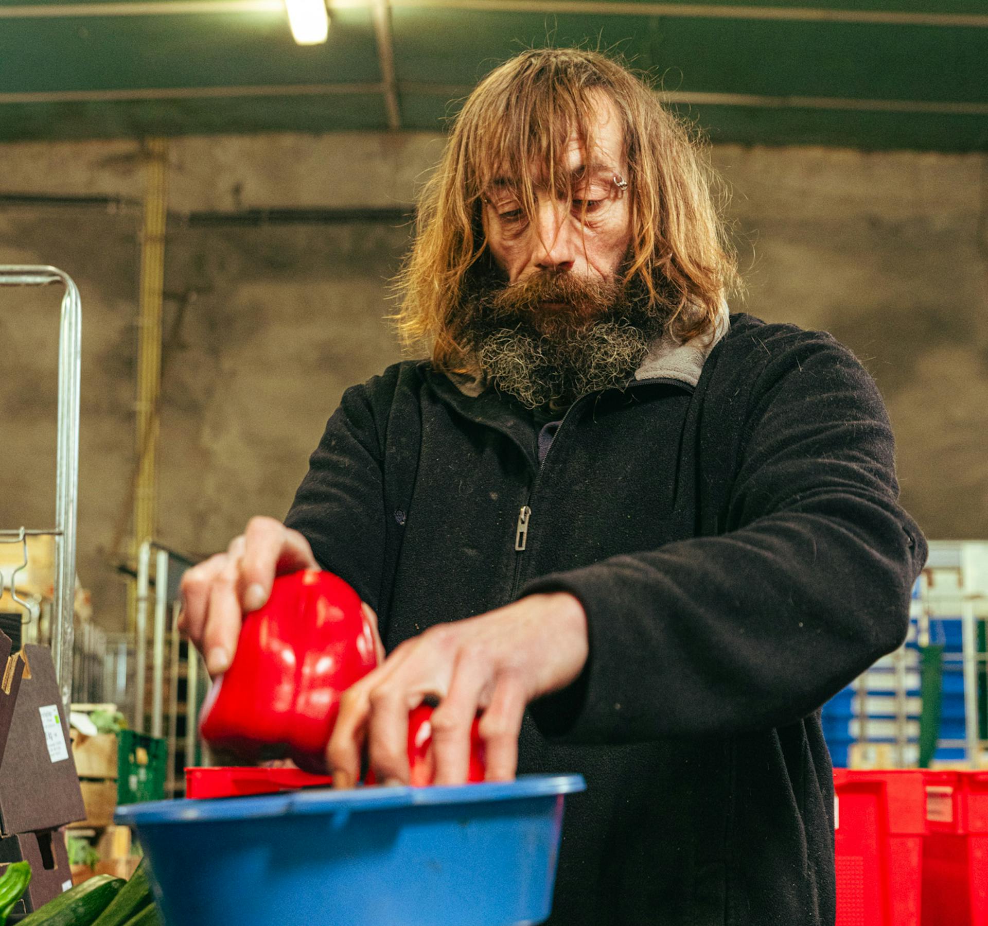 Dirk haalt paprika's uit een bakje om die te wegen. Herbruikbare bakken voor de pakketten op de achtergrond.