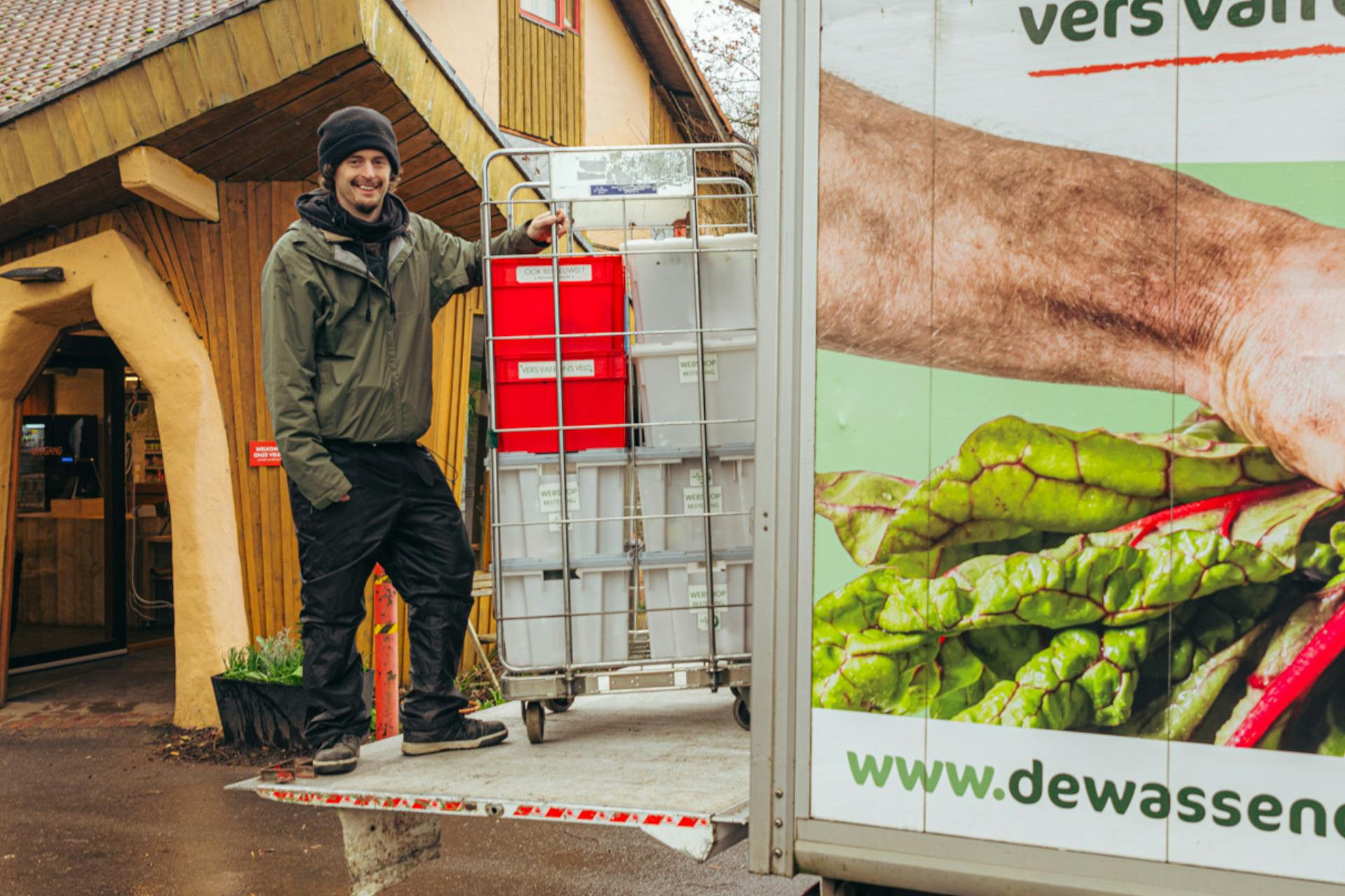 Siebe buiten aan de ingang van de bio-superette op de laadklap van een vrachtwagen met een rek vol bioboxen