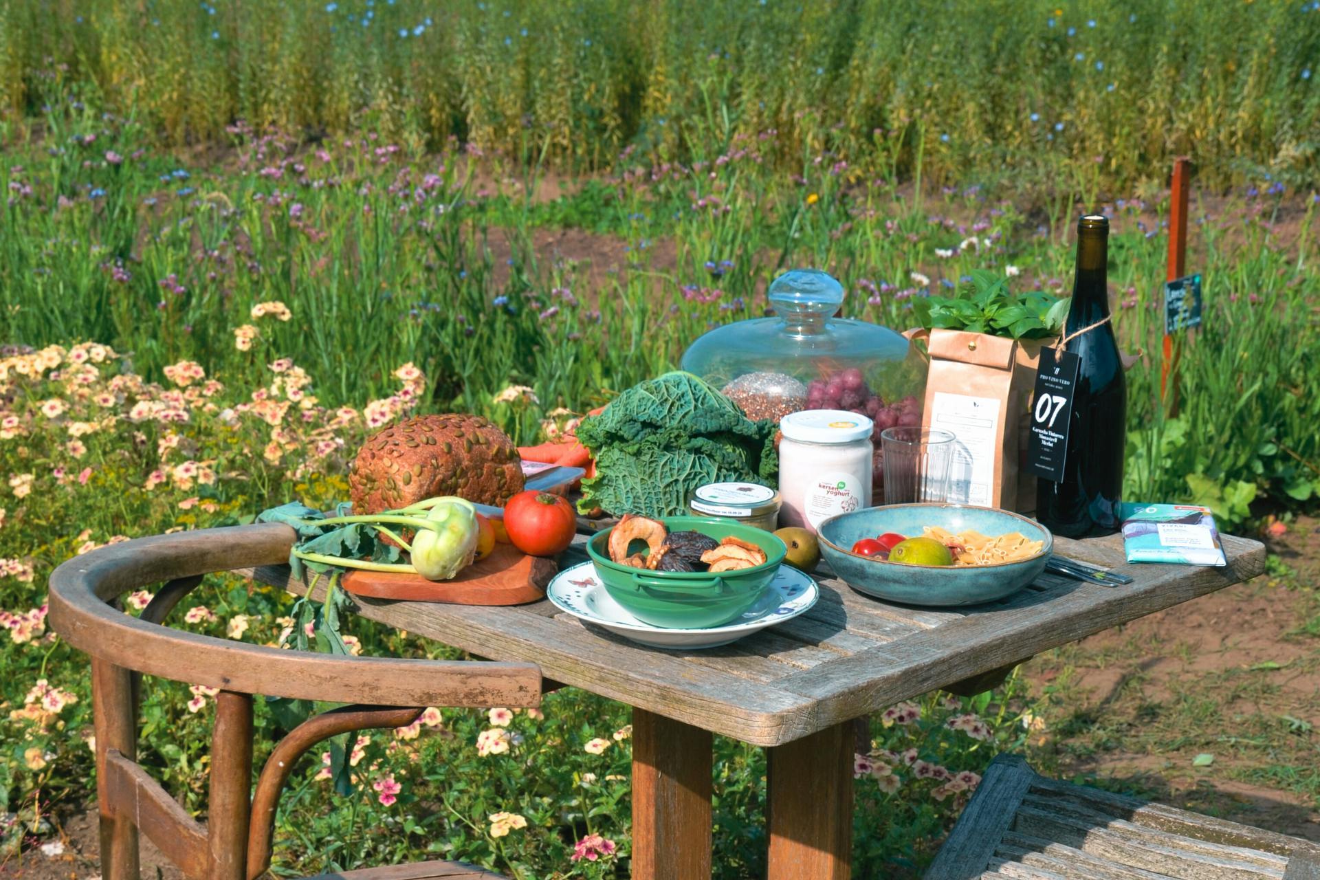Foto van een tafel in een groene omgeving die volgeladen staat met groenten, fruit en andere korteketenproducten van De Wassende Maan