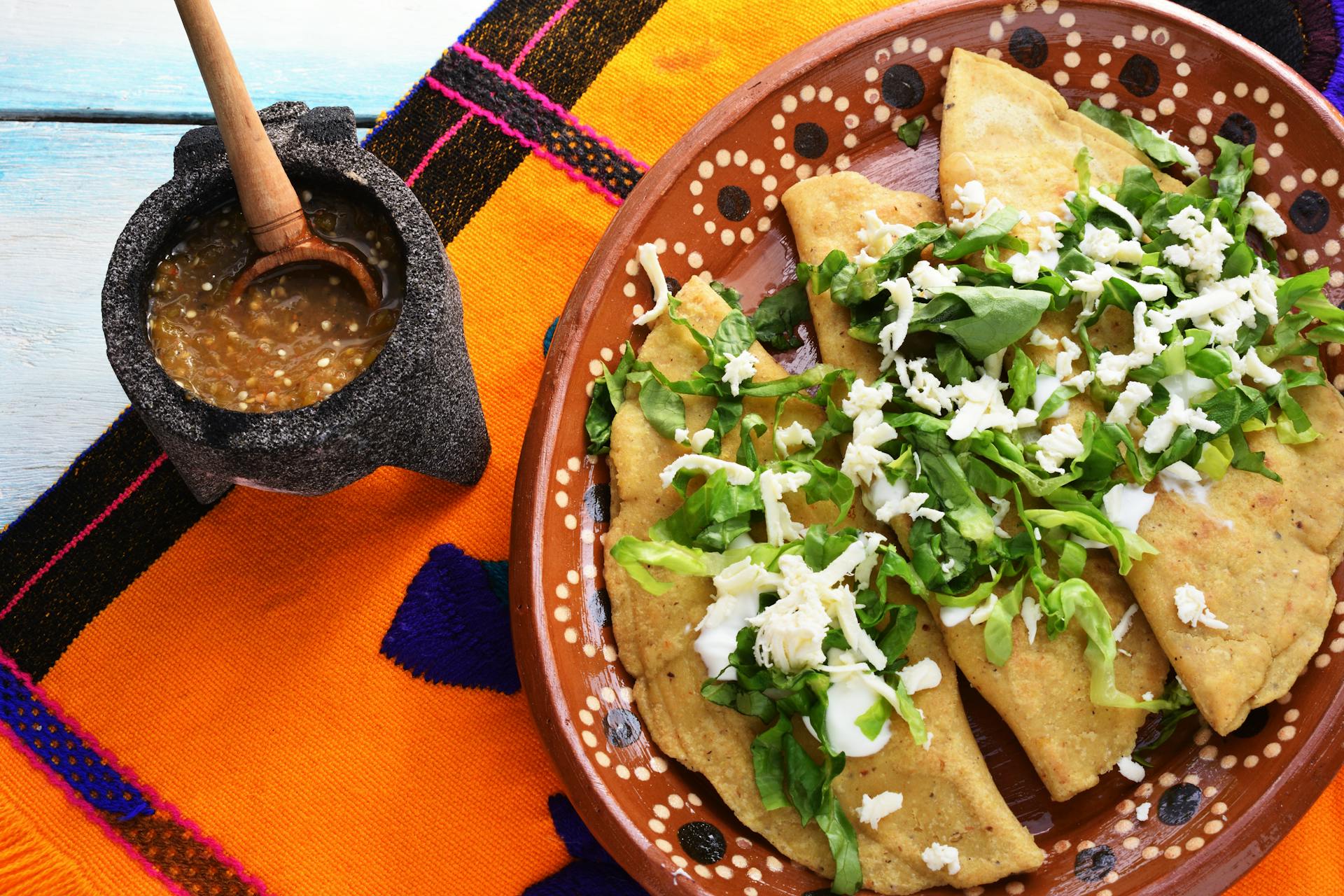 Bord met quesadilla's met kip, courgette en rode ui en extra saus on the side