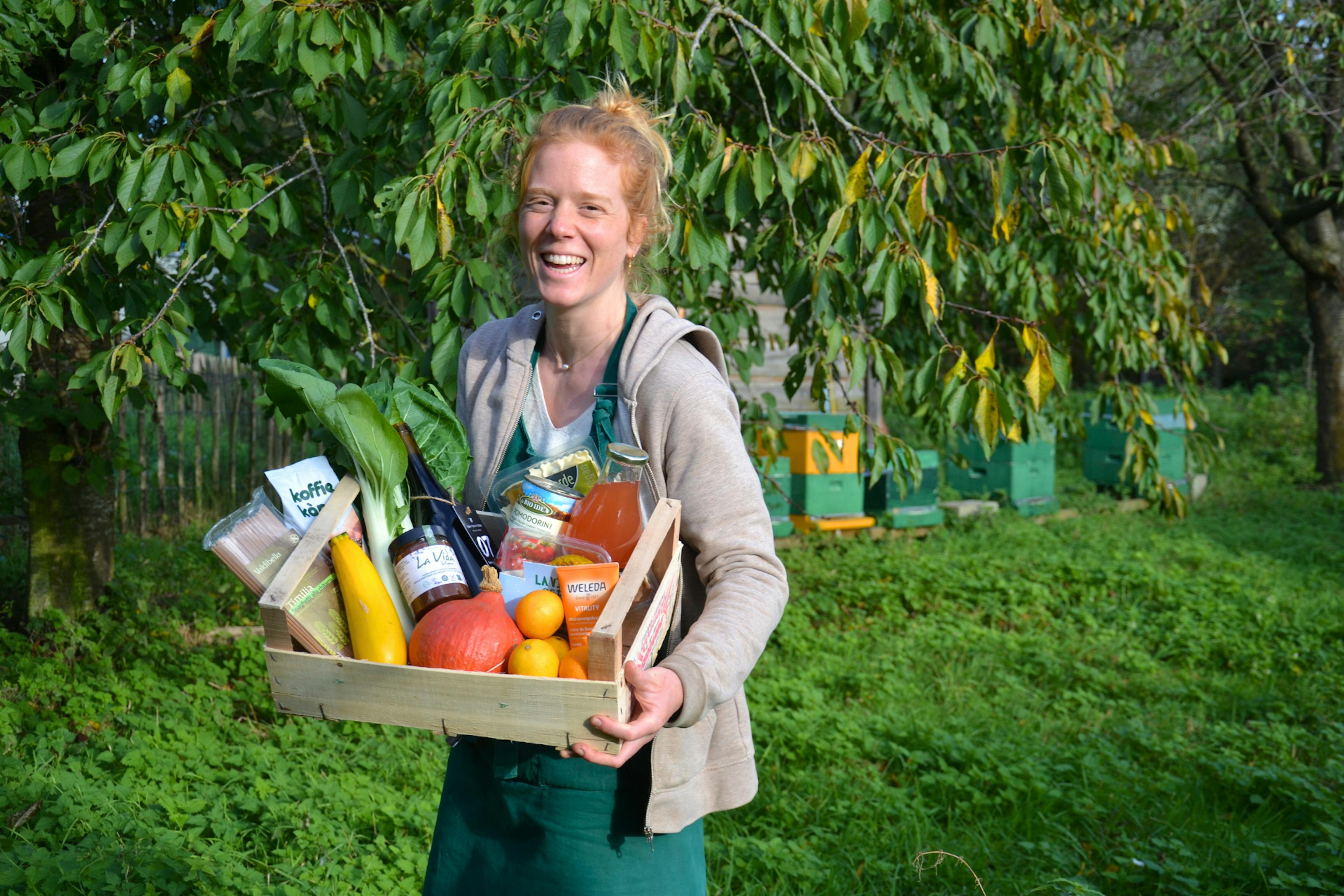 Foto van een vrouw in een groene omgeving die een webshopbestelling van De Wassende Maan in haar handen heeft