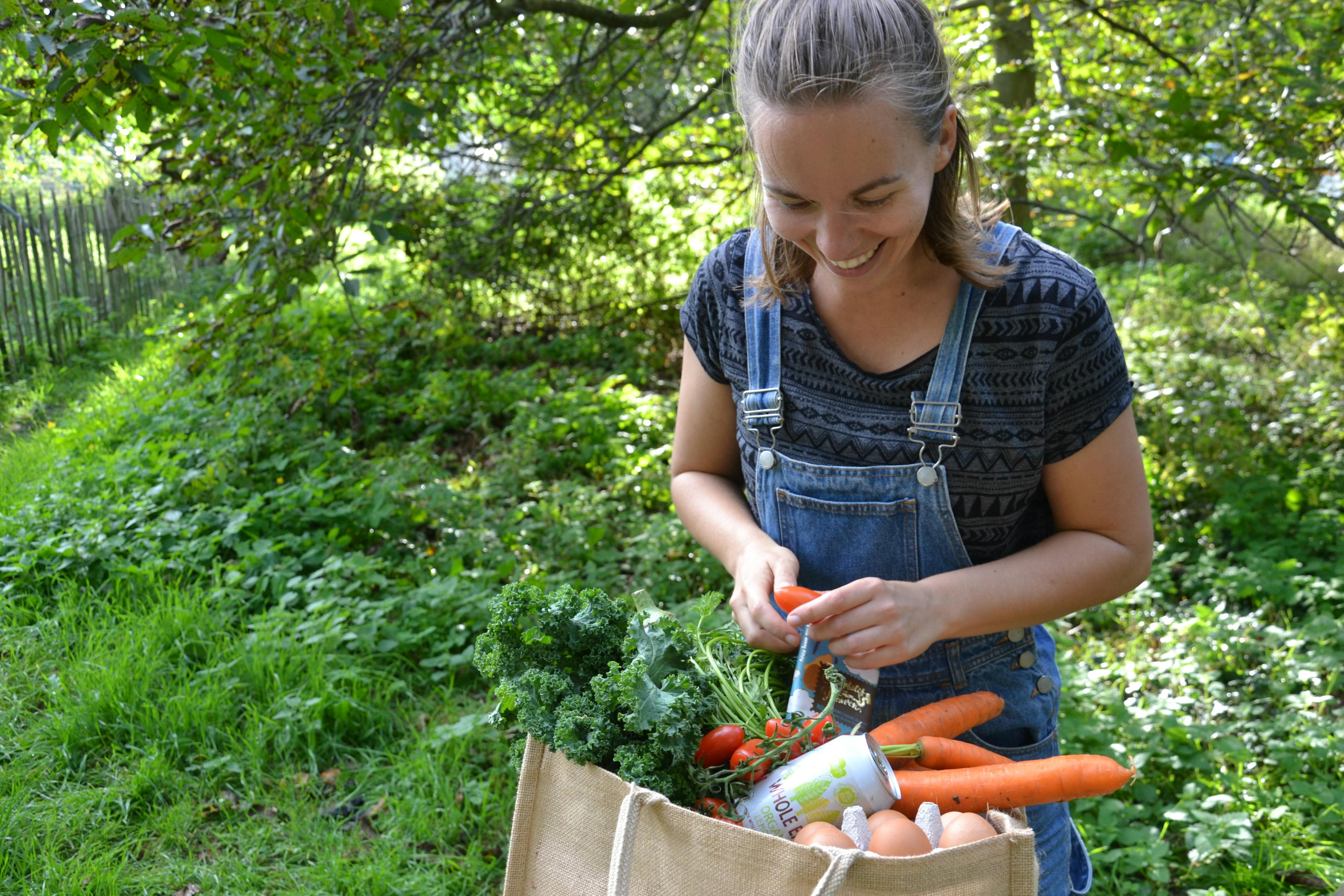Foto van een vrouw in een groene omgeving die een webshopbestelling van De Wassende Maan uitpakt