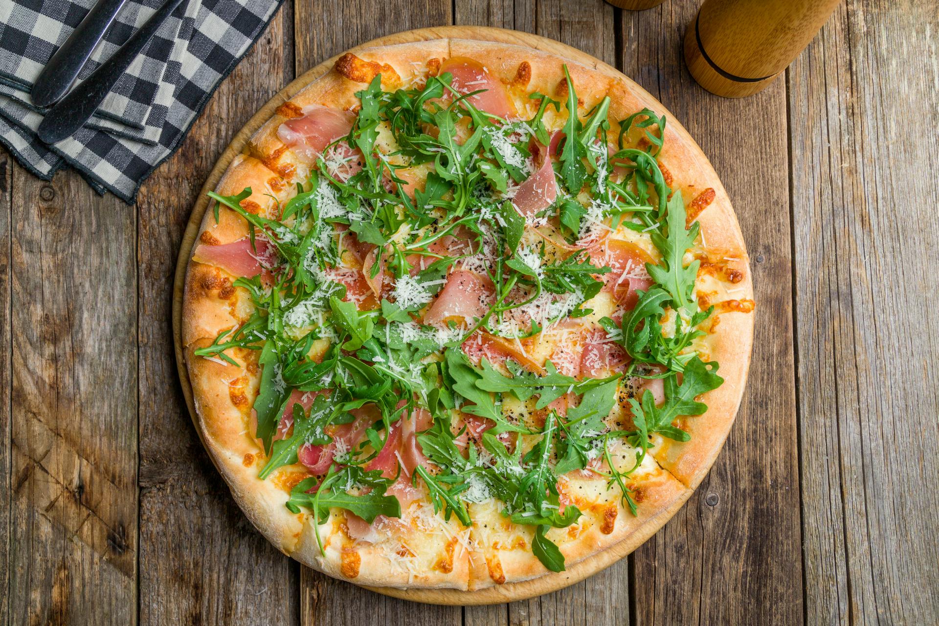 Pizza op houten tafel met rucola en pompoen