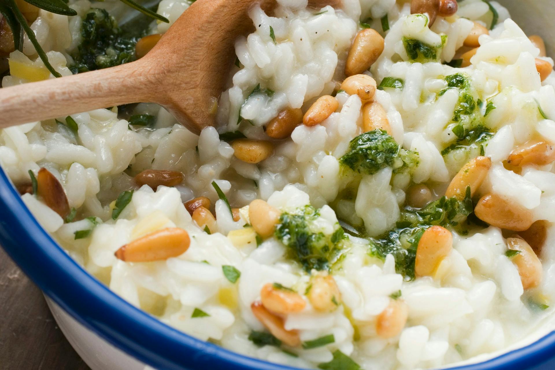 Risotto met pijnboompitten en pesto met een houten lepel in