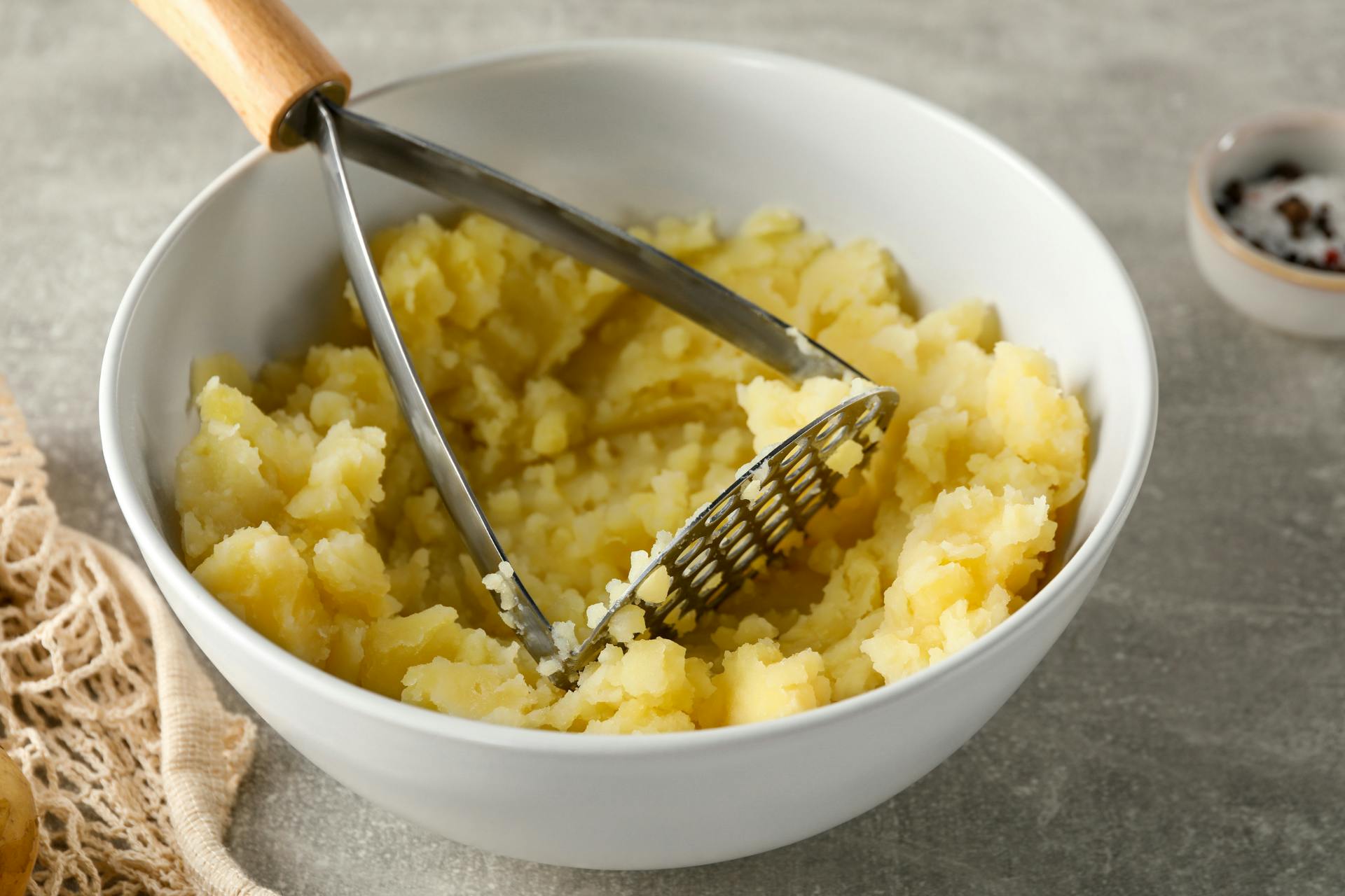 Kom met stamper en aardappelen