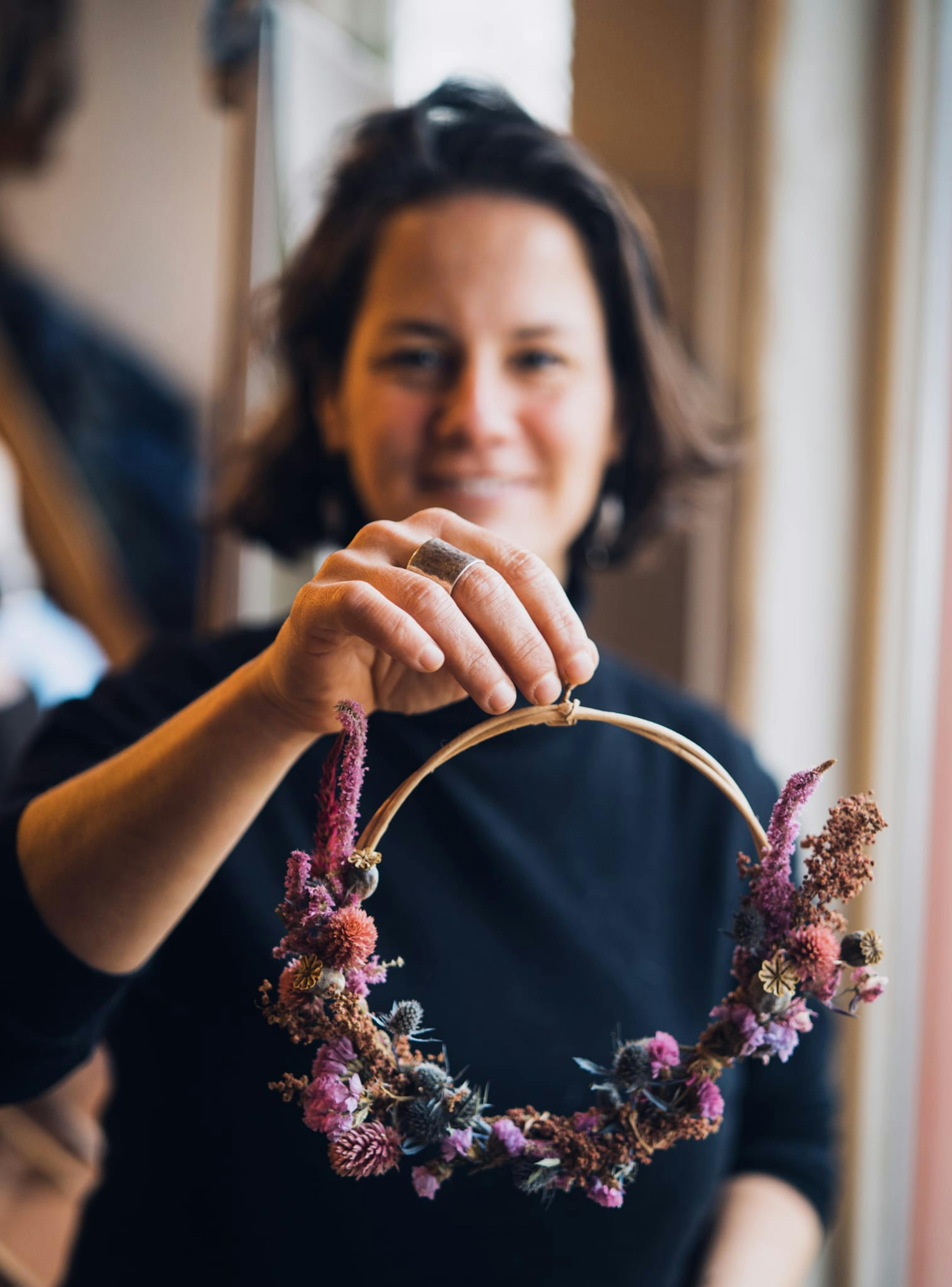 Foto van een deelnemer met een zelfgemaakte droogbloemenkrans